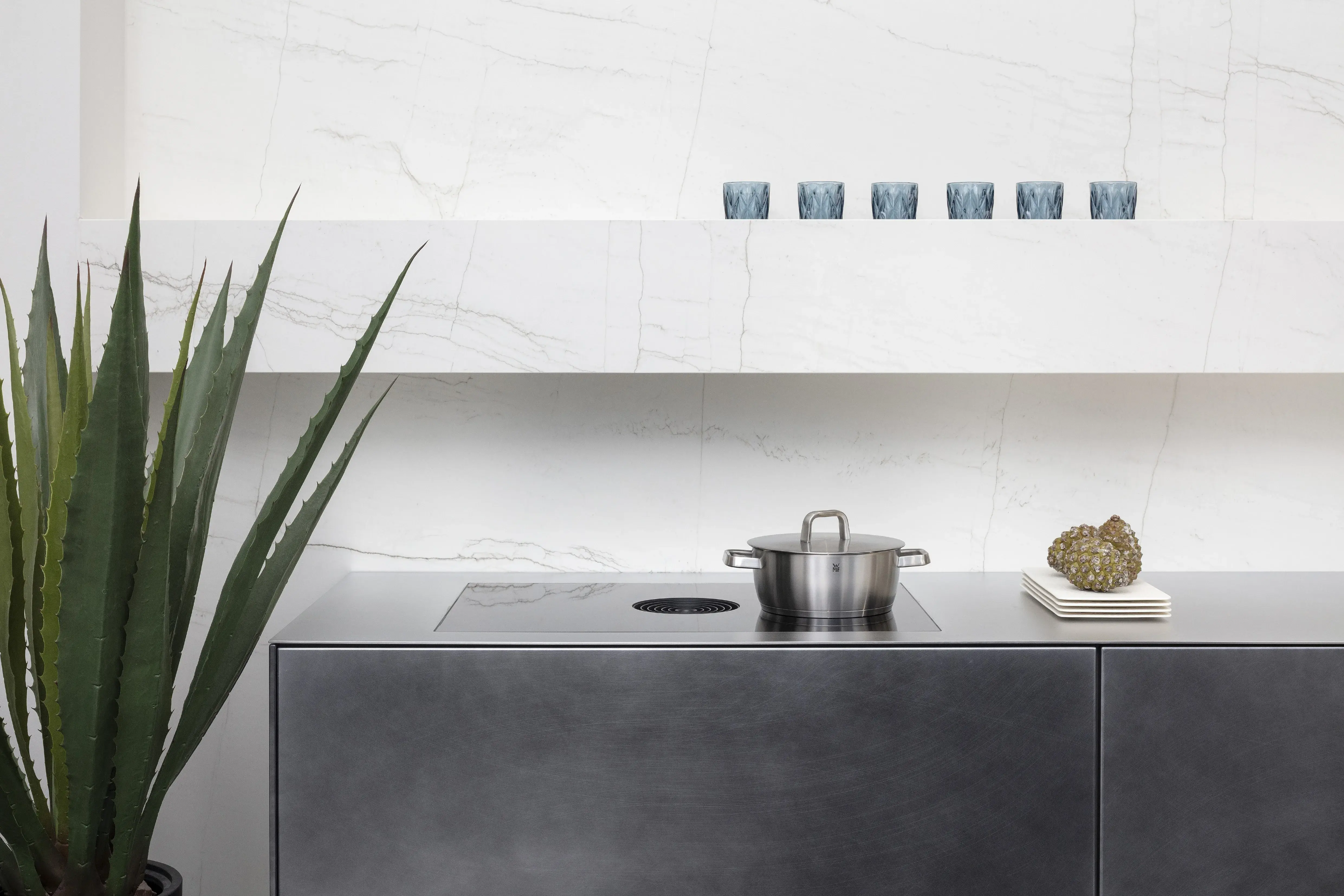 Front: Industriestahl Metalliclack geschliffen AV6000 NCS Mattlack APL: Franke Edelstahl 6 mm Geräte: Bora Spüle Armaturen: Franke  Features: Metallfront, Spülbecken in APL integriert (aus einem Guss), Oberschränke mit Lowboard-Charakter, integrierter Arbeitsplatz, dunkler Korpus mit Aluminium-Abschlussleiste, Wärmeschublade mit Gittereinsatz.